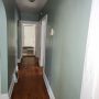 view down common hallway from dining room towards rear large bedroom with door to rear enclosed porch