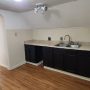 view into kitchen sink, counter and cabinet area from hallway in front of bathroom doorway